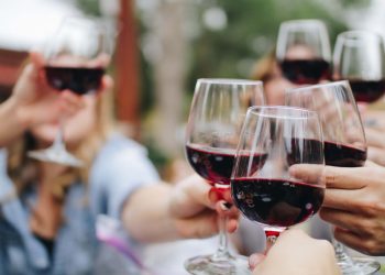 Groep vrienden met ieder een glas rode wijn in de hand proosten samen