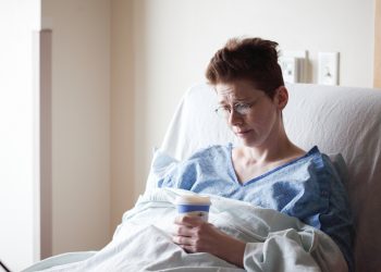 Vrouw in ziekenhuisbed met bekertje in de hand